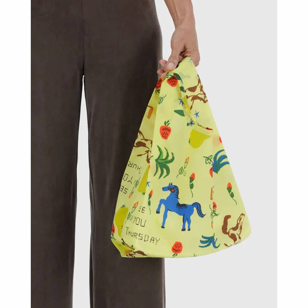 Person holding a colorful bag with animal illustrations and text.