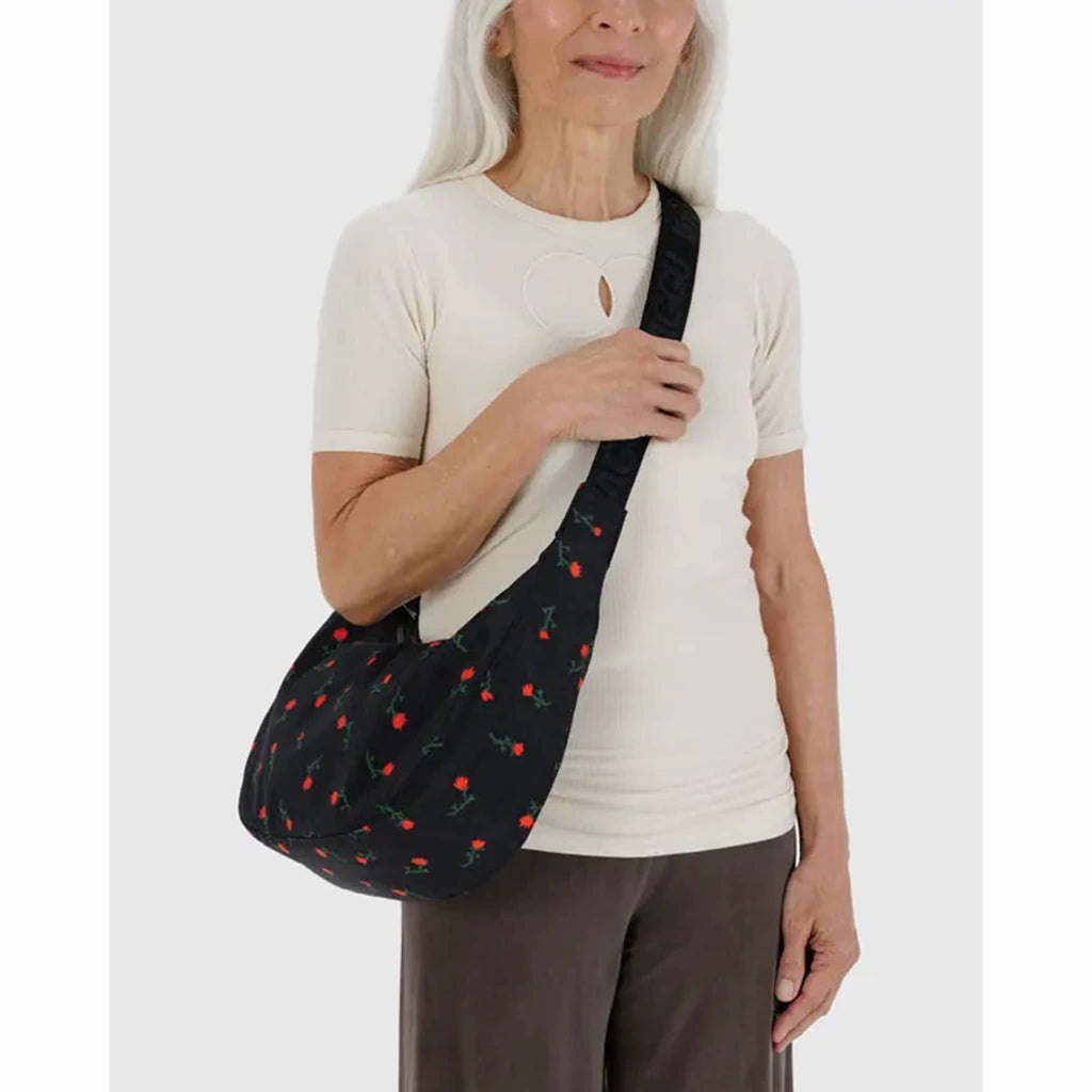 Person holding a Baggu Painted Wildflower medium ripstop nylon crescent bag.