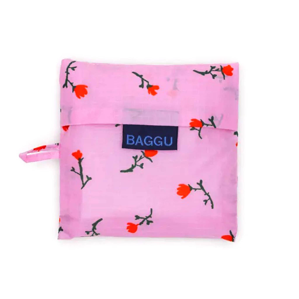 Pink reusable bag with floral pattern in matching pouch with 'BAGGU' brand label on a white background.