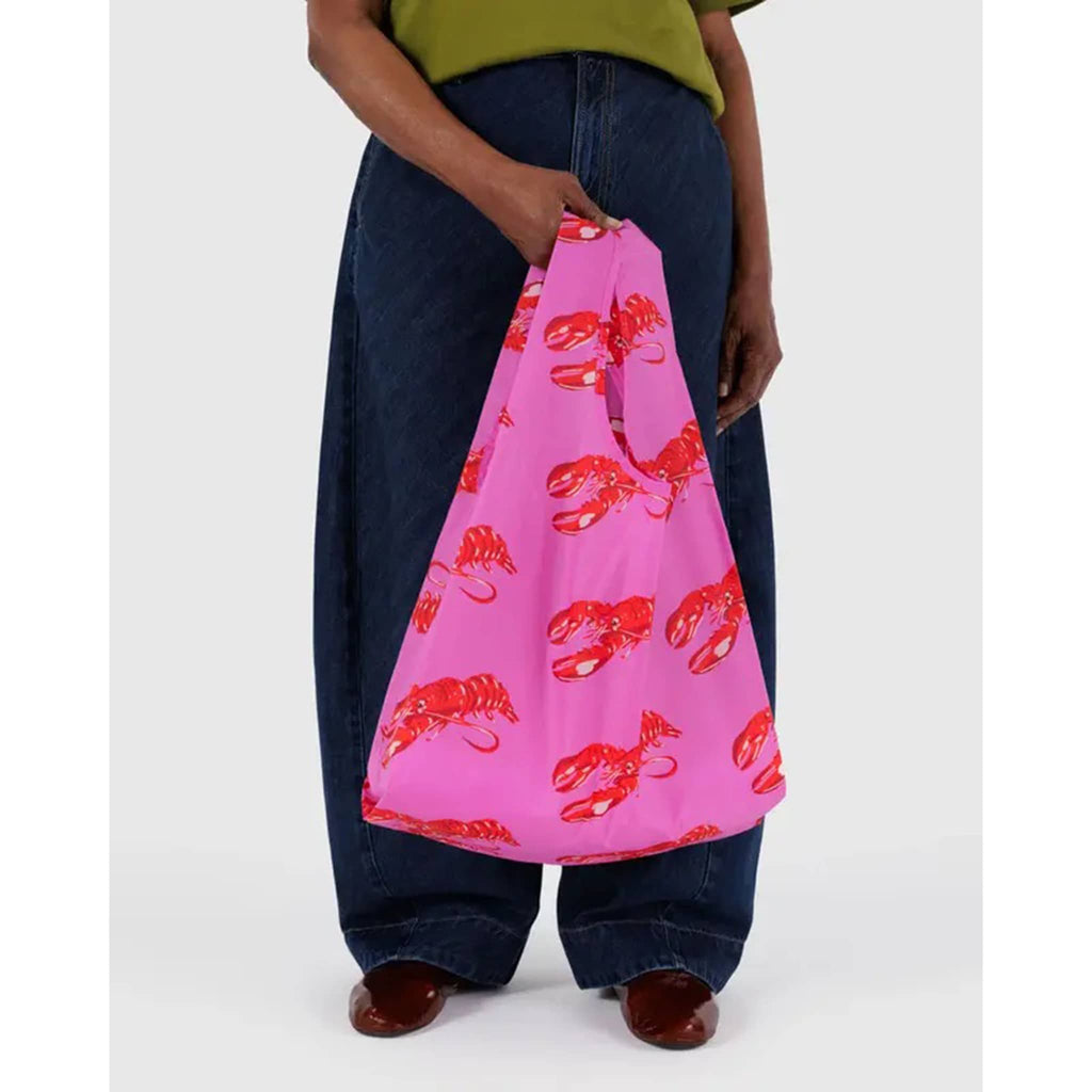 Baggu Pink Lobster standard ripstop nylon reusable bag, in models hand.
