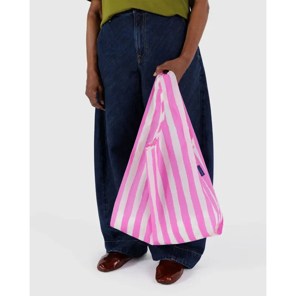 Baggu Pink Painted Stripe standard ripstop nylon reusable bag, in models hand.