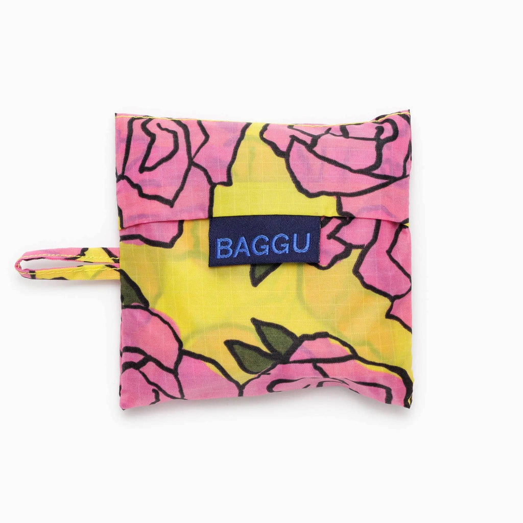 Baggu baby size eco-friendly recycled ripstop nylon reusable tote bag with a pink Rose pattern on a yellow background, in matching pouch.