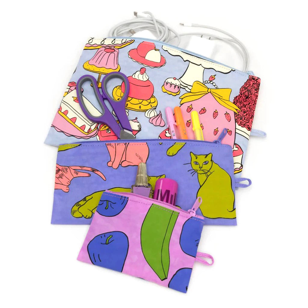 Baggu recycled ripstop nylon flat zipper pouches, set of 3 in assorted sizes with prints from the Still Life collection, unzipped and filled with cosmetics, art supplies and charging cords.