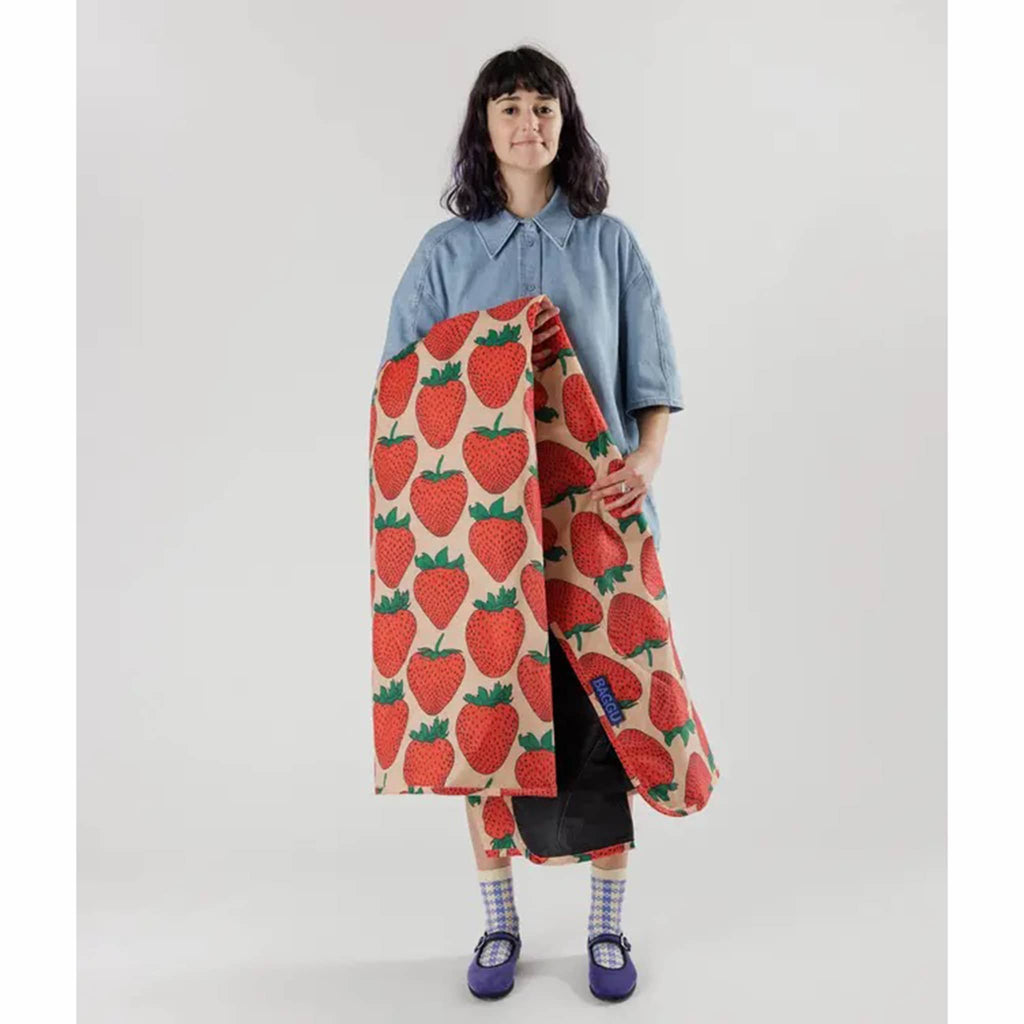 Person holding the Baggu Strawberry puffy recycled ripstop nylon and polyester picnic blanket.