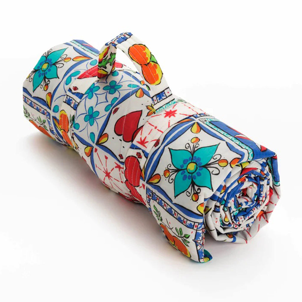 Baggu sunshine tile puffy recycled ripstop nylon and polyester picnic blanket, rolled up with strap.