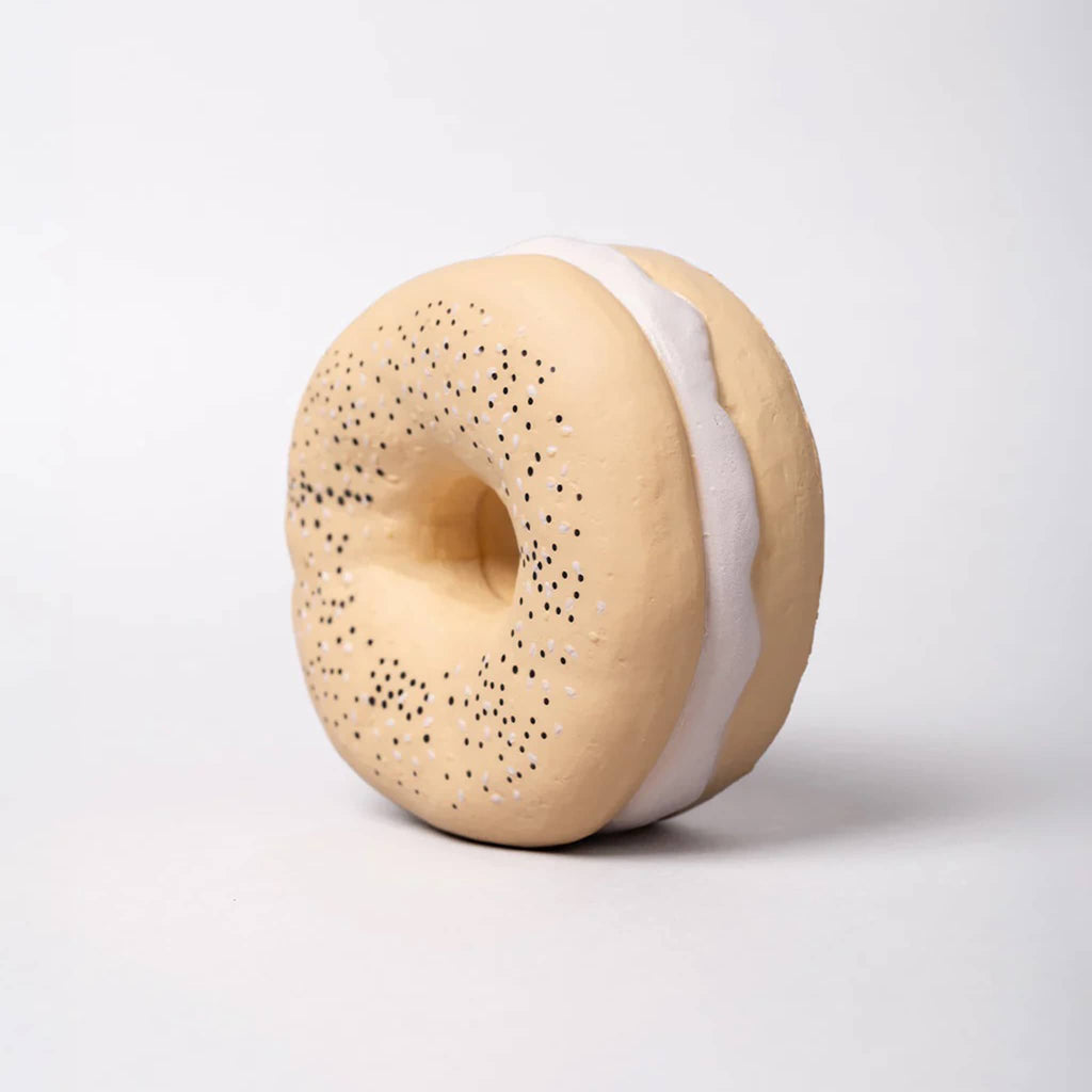 Bagel shaped fidget toy with speckled top and white filling standing up, front angle view on a light gray background.