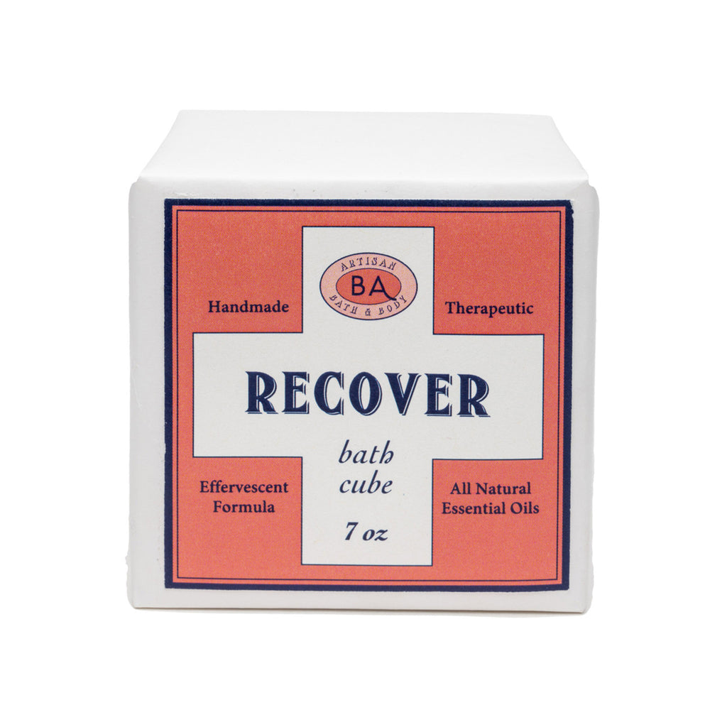 Baudelaire Recover therapeutic, effervescent bath cube in white paper wrapping with orange label, front view.