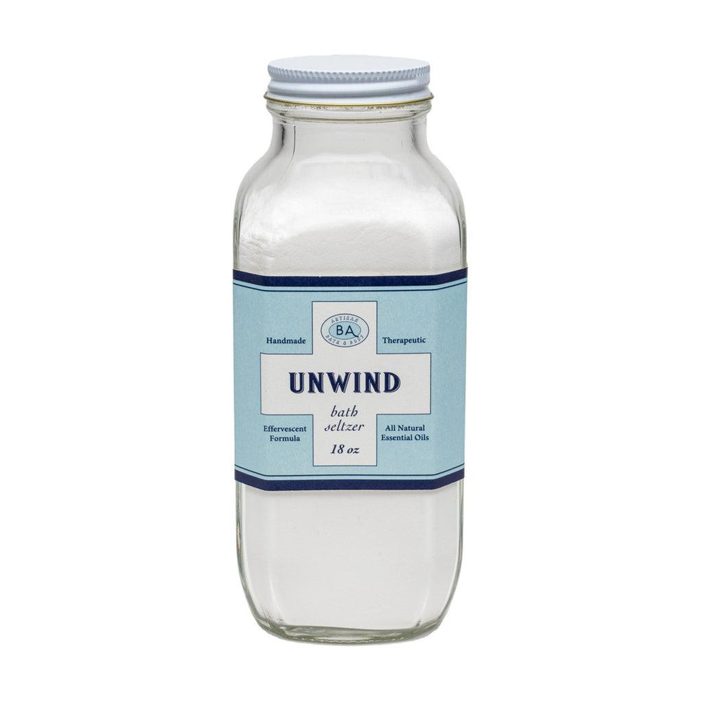 Baudelaire Unwind therapeutic, effervescent bath seltzer salts in clear glass bottle with light blue label, front view.