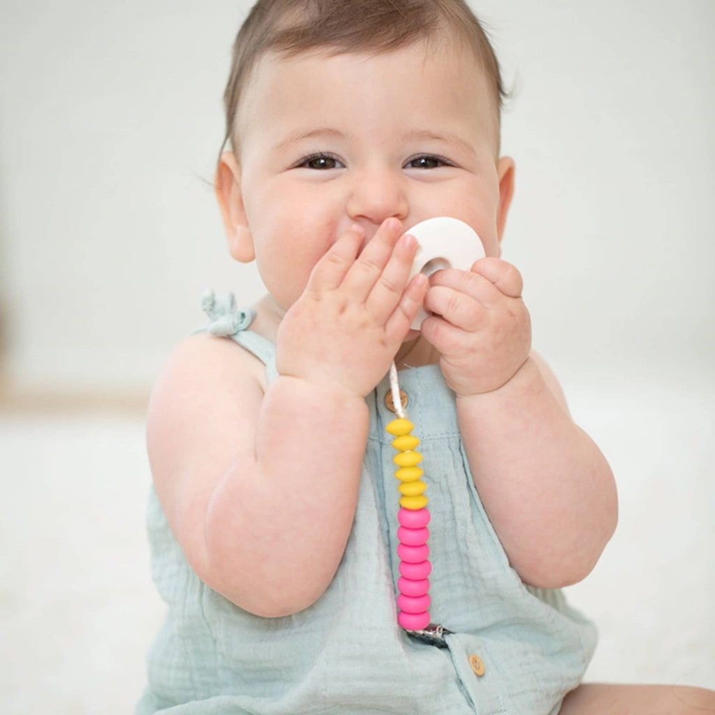 Bella Tunno Punch Duo Baby Pacifier Clip with silicone beads in bright yellow and pink, with baby.