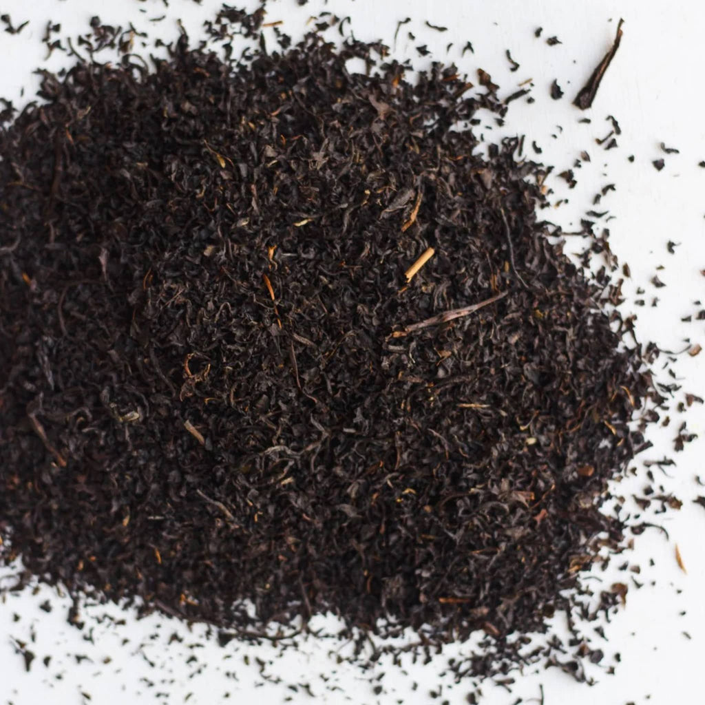 Close-up of dark brown tea leaves on a white background.