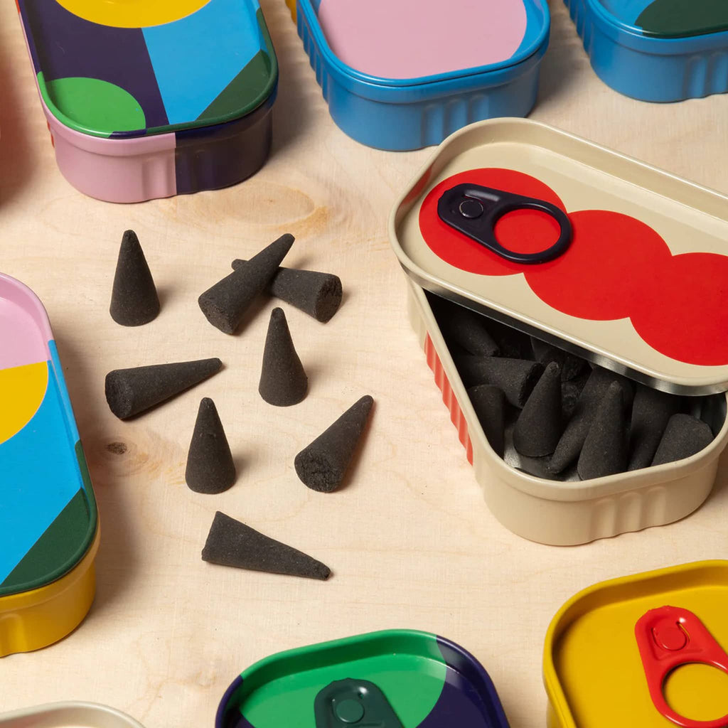 Tinned Goods sandalwood incense cones with packaging and other colorful tins on a wood background.