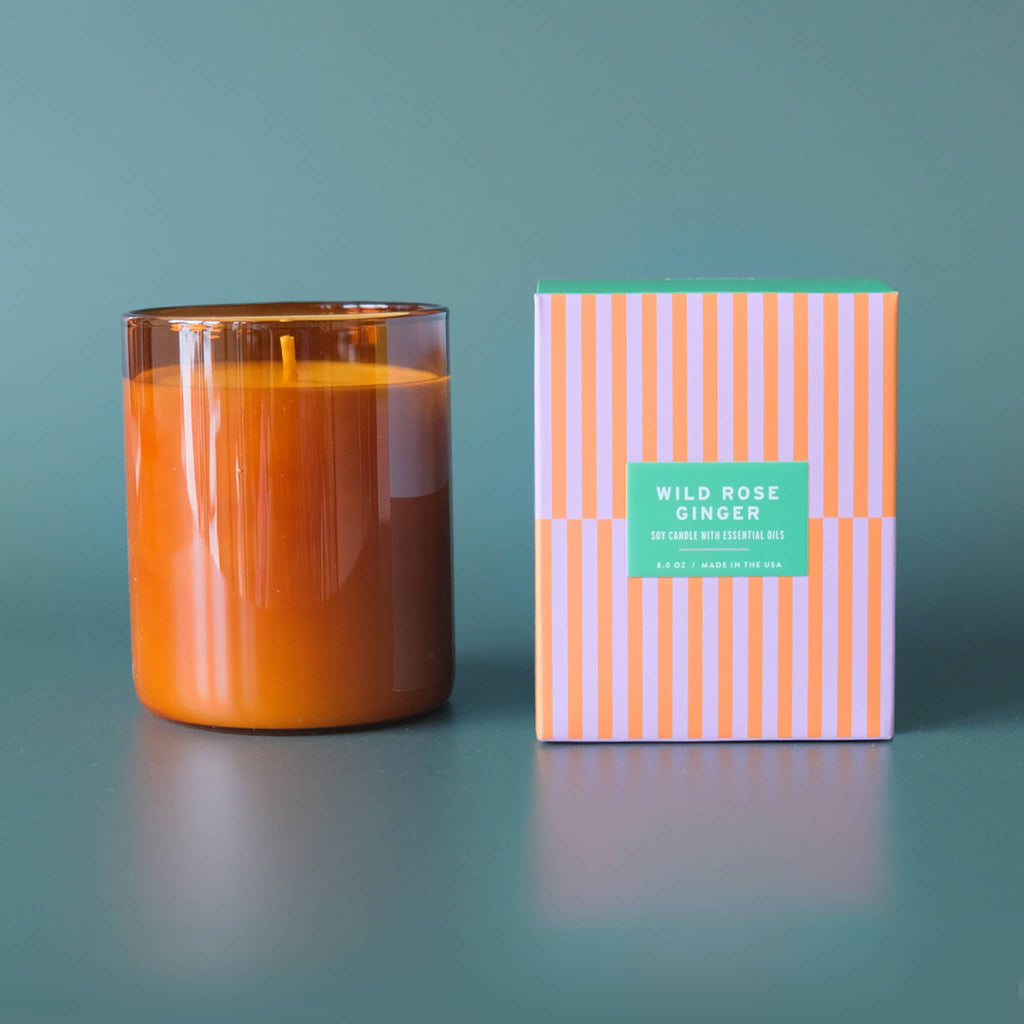 Botanica Essentials 8 ounce Wild Rose and Ginger scented soy candle with essential oils in amber glass vessel with striped box packaging.