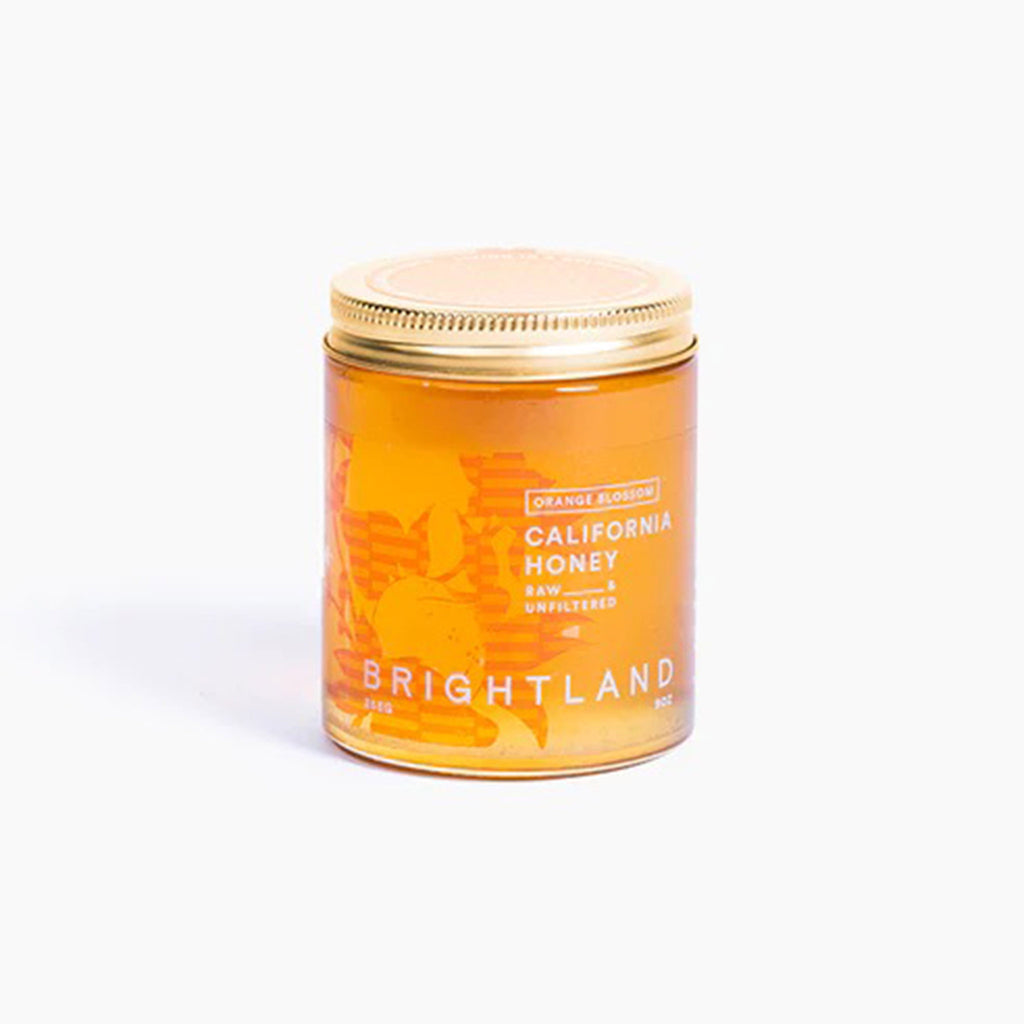Brightland Raw & Unfiltered California Orange Blossom Honey in glass jar with gold lid.