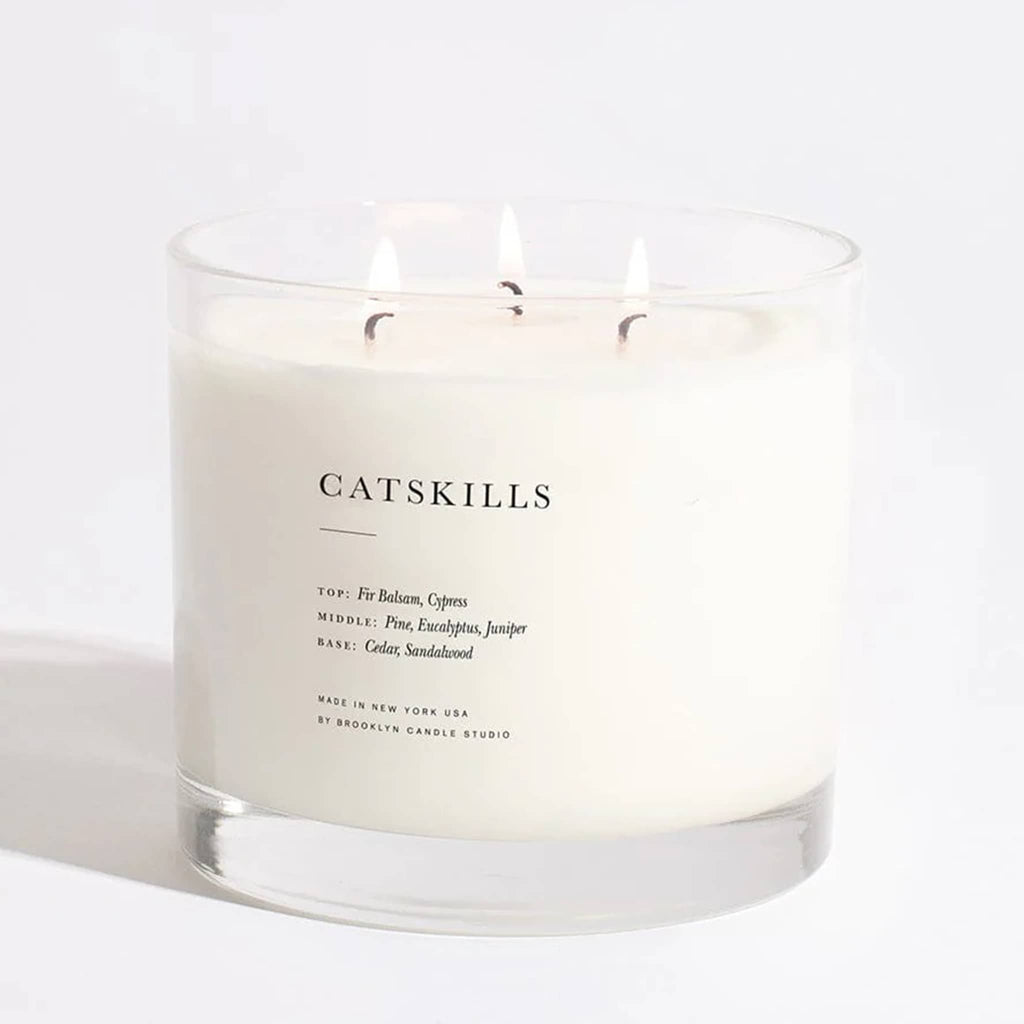 Brooklyn Candle Studio Catskills scented triple wick xl maximalist candle in clear glass vessel, wicks are lit.