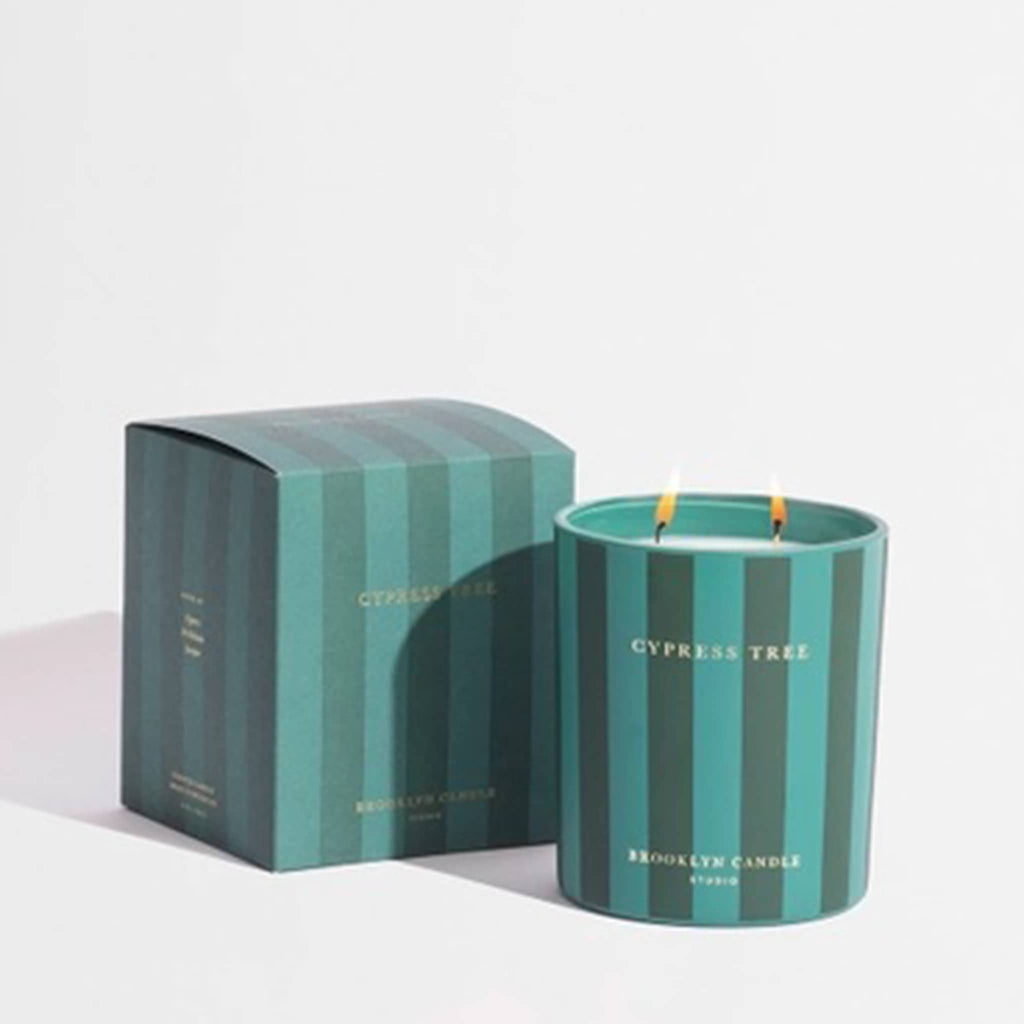 Green striped candle and packaging with 'Cypress Tree' branding on a light gray background.