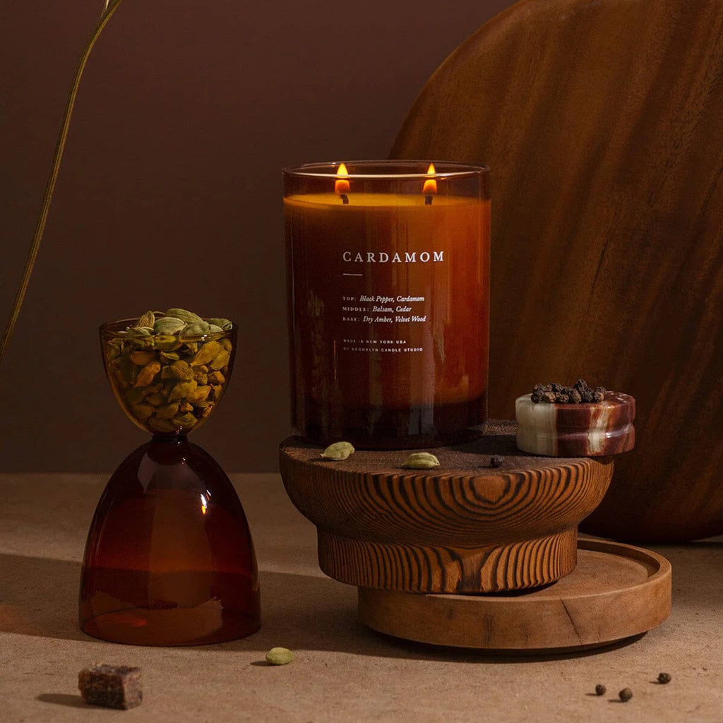 Candle labeled 'Cardamom' with decorative elements on a wooden surface.