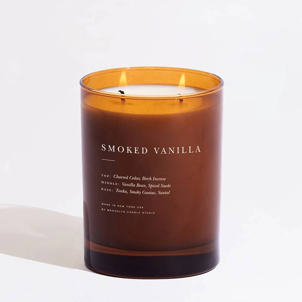 Smoked Vanilla candle in amber glass container, 2 wicks lit, on a white background.