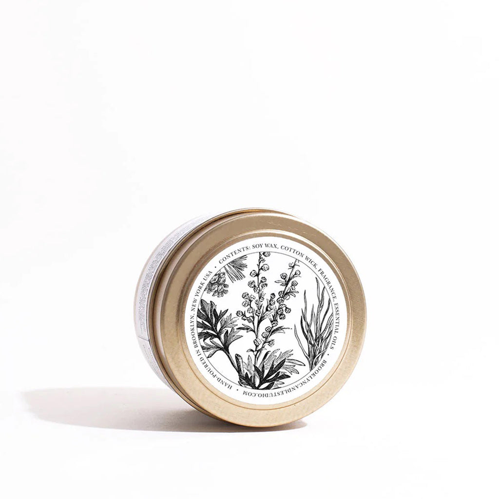 Top of lid of Brooklyn Candle Studio Leather Jacket scented candle in brushed gold travel tin with an illustration of botanicals.