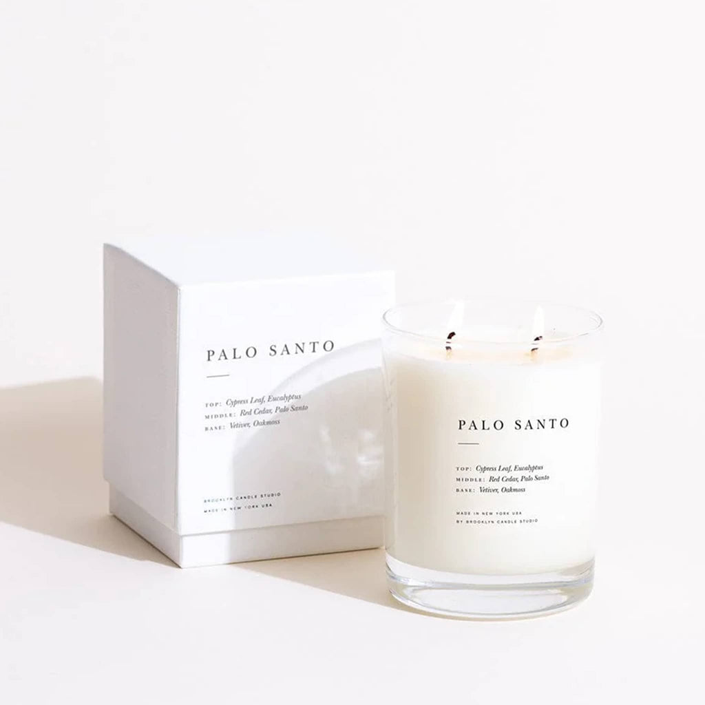 Palo Santo candle with double-wicks lit with box packaging on a white background.