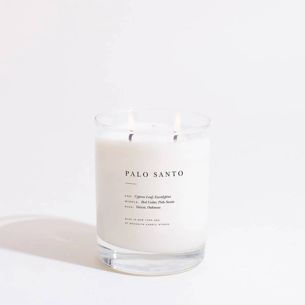 Palo Santo candle with double-wicks lit on a white background.