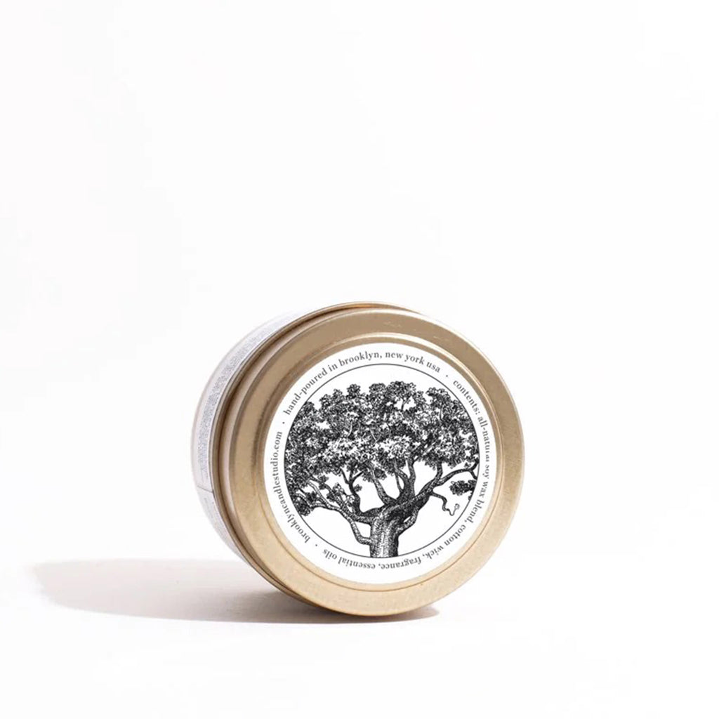 Top of lid of Brooklyn Candle Studio Palo Santo scented candle in brushed gold travel tin with an illustration of a palo santo tree.