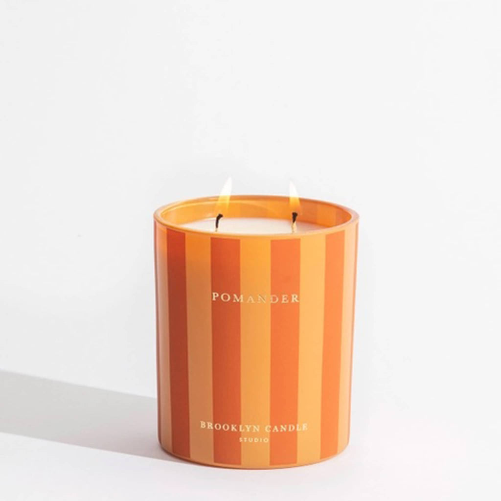 Striped candle with 'Pomander' branding on a white background.