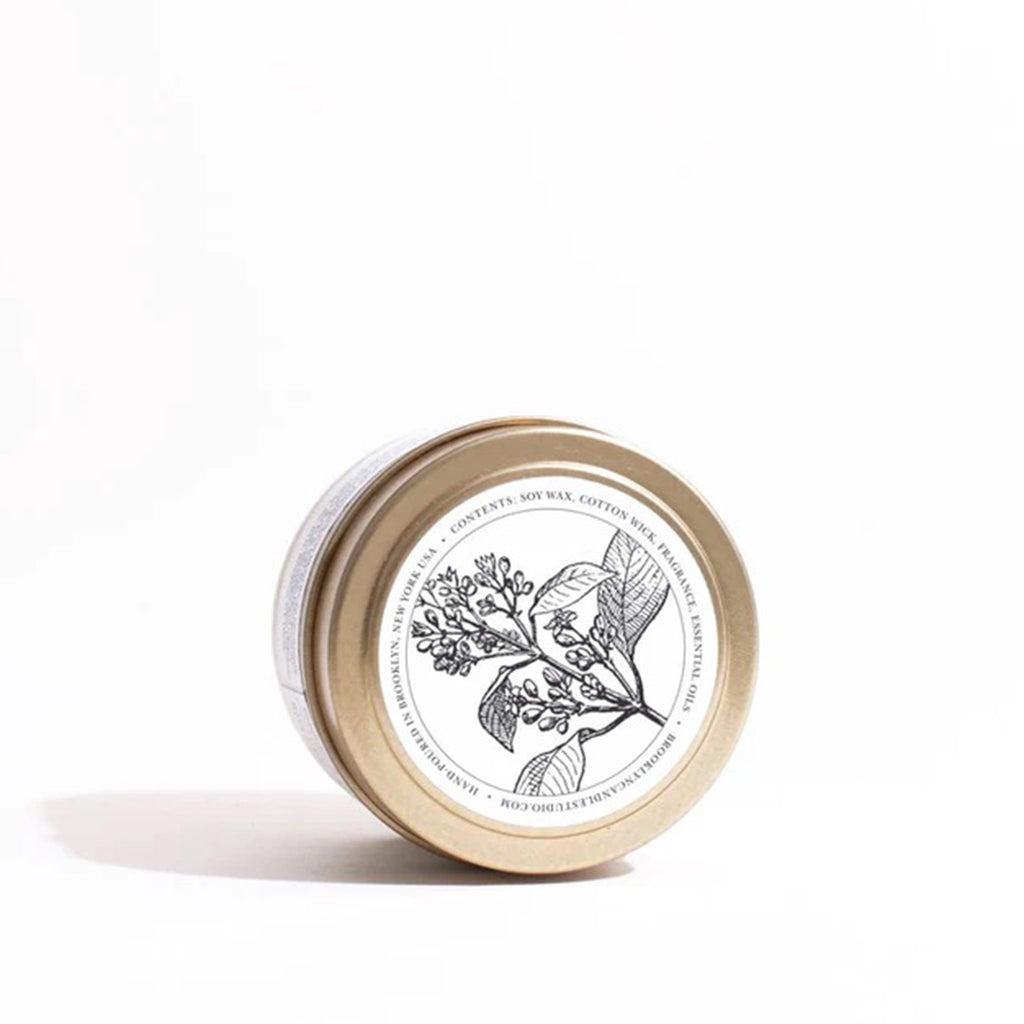 Top of lid of Brooklyn Candle Studio Santal scented candle in brushed gold travel tin with an illustration of santal branch.