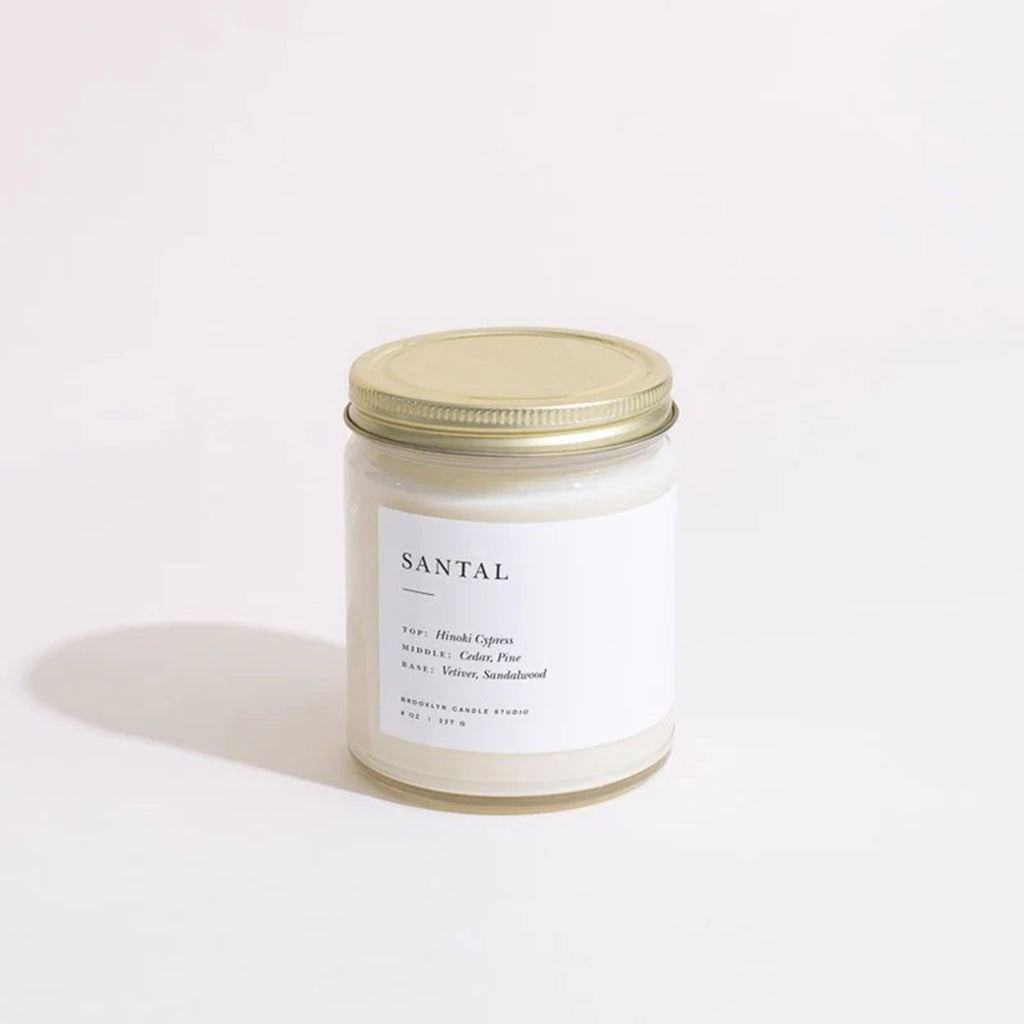Brooklyn Candle Studio Santal scented candle in a straight sided clear glass jar with minimalist label and brushed gold screw-on lid.