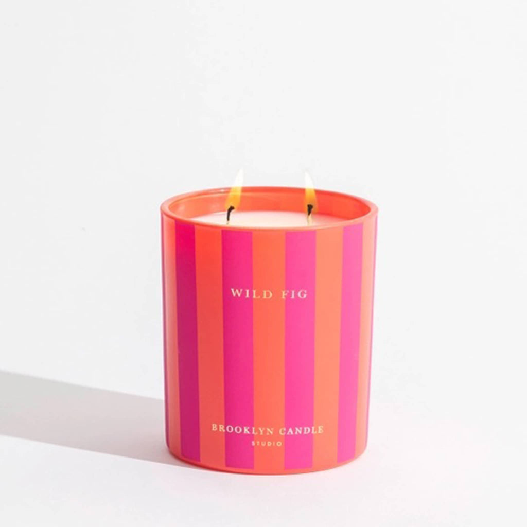 Pink and orange striped candle with 'Wild Fig' and 'Brooklyn Candle Studio' text on a white background.