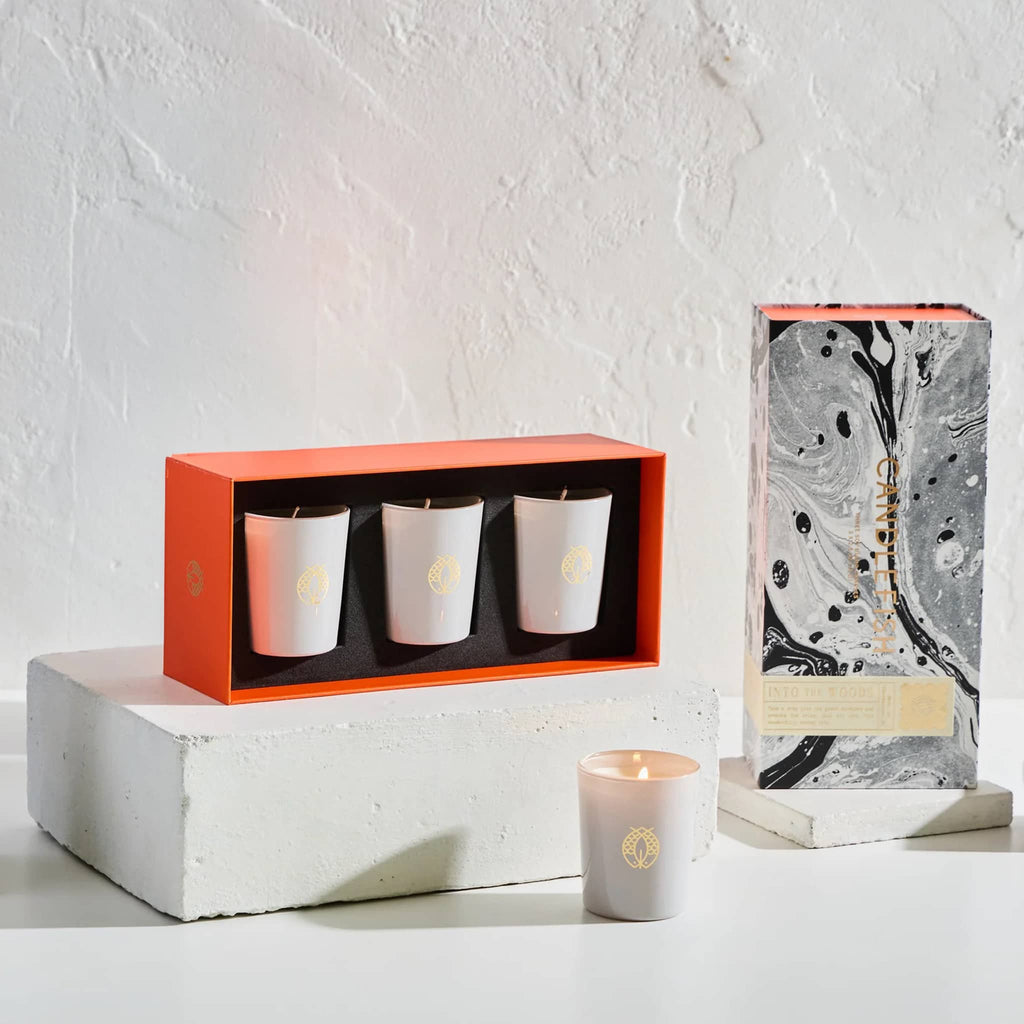 Candlefish Into the Woods scented votive candle gift set, set of 3 candles in frosted white glass vessels in black and white patterned gift box packaging, open to show candles nesting in orange inner box.