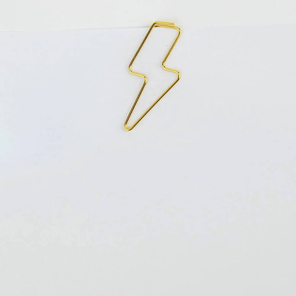 Chez Gagne Gold Tone Lightning Bolt Paper Clip shown clipped on a piece of paper.