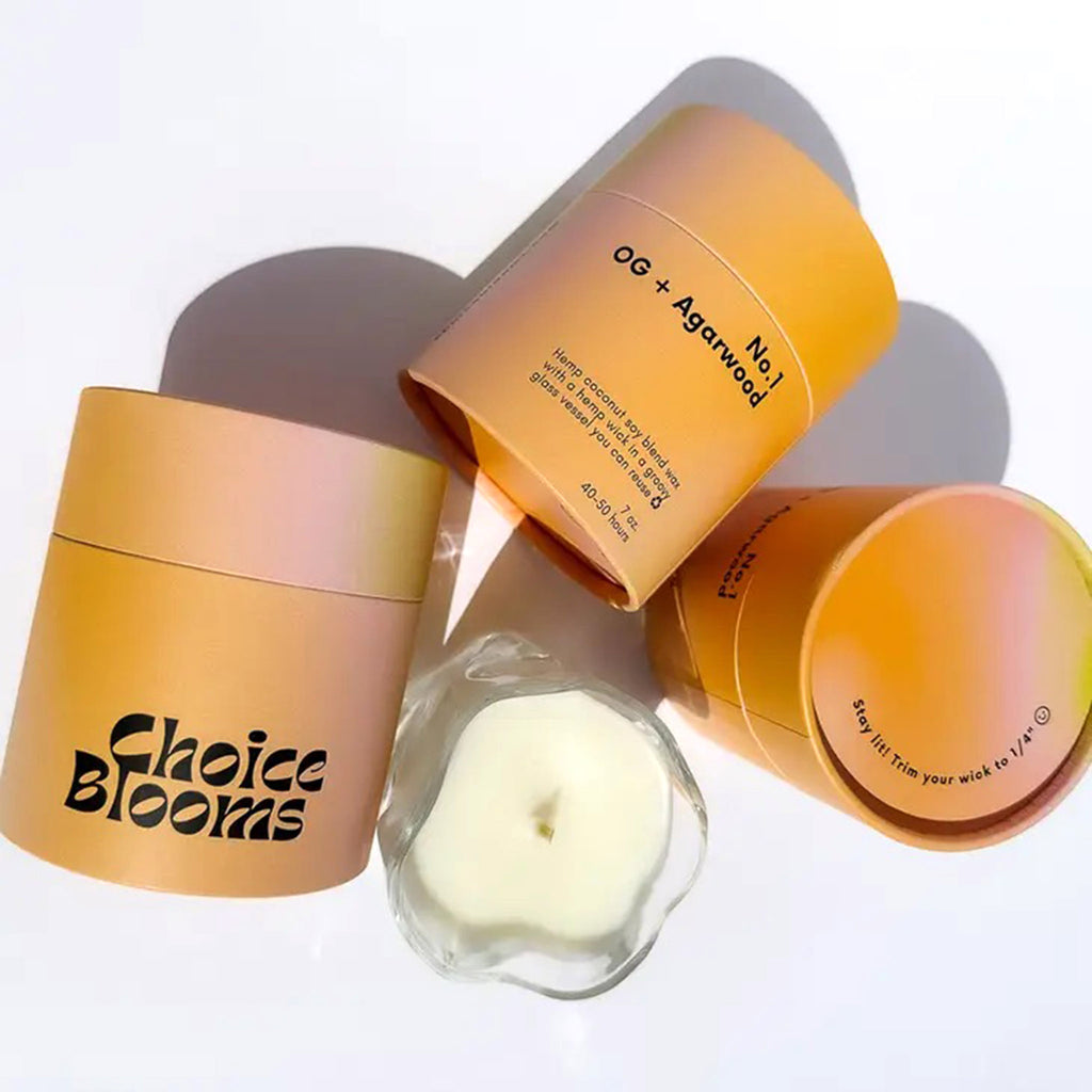 Choice Blooms No. 1 OG and Agarwood scented candle made from a hemp, coconut and soy wax blend, in a curvy clear glass vessel surrounded by 3 ombre orange canisters to show all sides of packaging.
