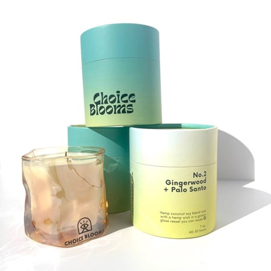 Choice Blooms No. 2 Gingerwood and Palo Santo scented candle made from a hemp, coconut and soy wax blend, in a curvy amber glass vessel surrounded by 3 ombre neon green to turquoise canisters to show all sides of packaging.