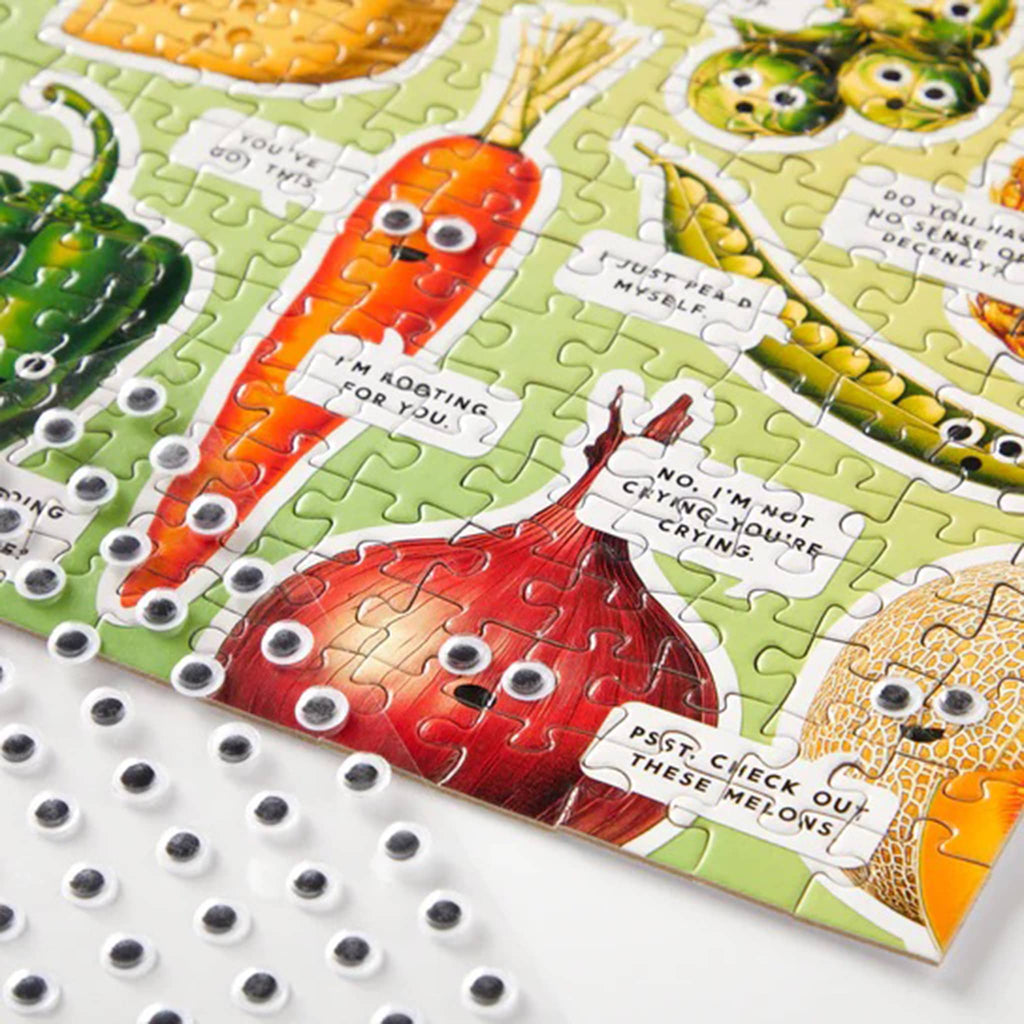 Jigsaw puzzle with cartoon vegetables on a green background with sheet of googly eyes.