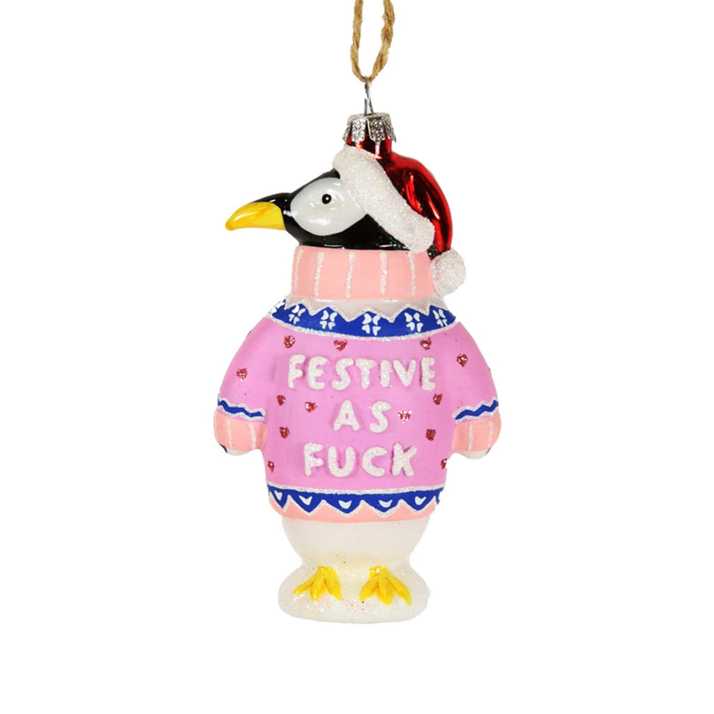 Cody Foster penguin glass holiday ornament, wearing a pink turtleneck sweater that says "festive as fuck" and a red stocking cap.