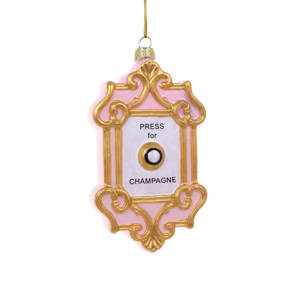 Cody Foster pink glass holiday tree ornament with gold filigree that looks like a wall plate with a "button" in the center and "press for champagne" in black lettering.