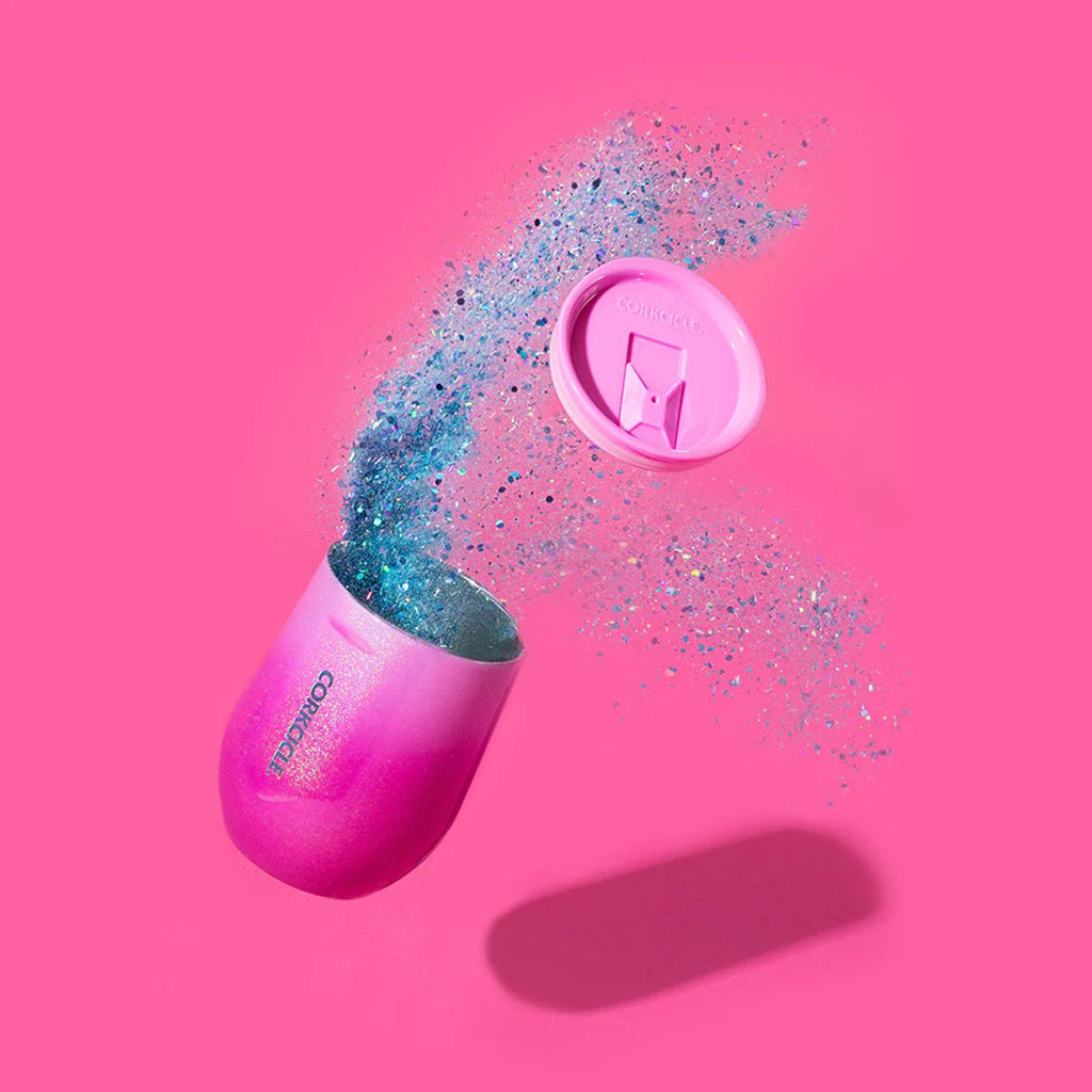 Corkcicle 12 ounce Ombre Unicorn Kiss glittery pink insulated stainless steel stemless cup with pink lid flying off and glitter coming out of the cup on a pink background.