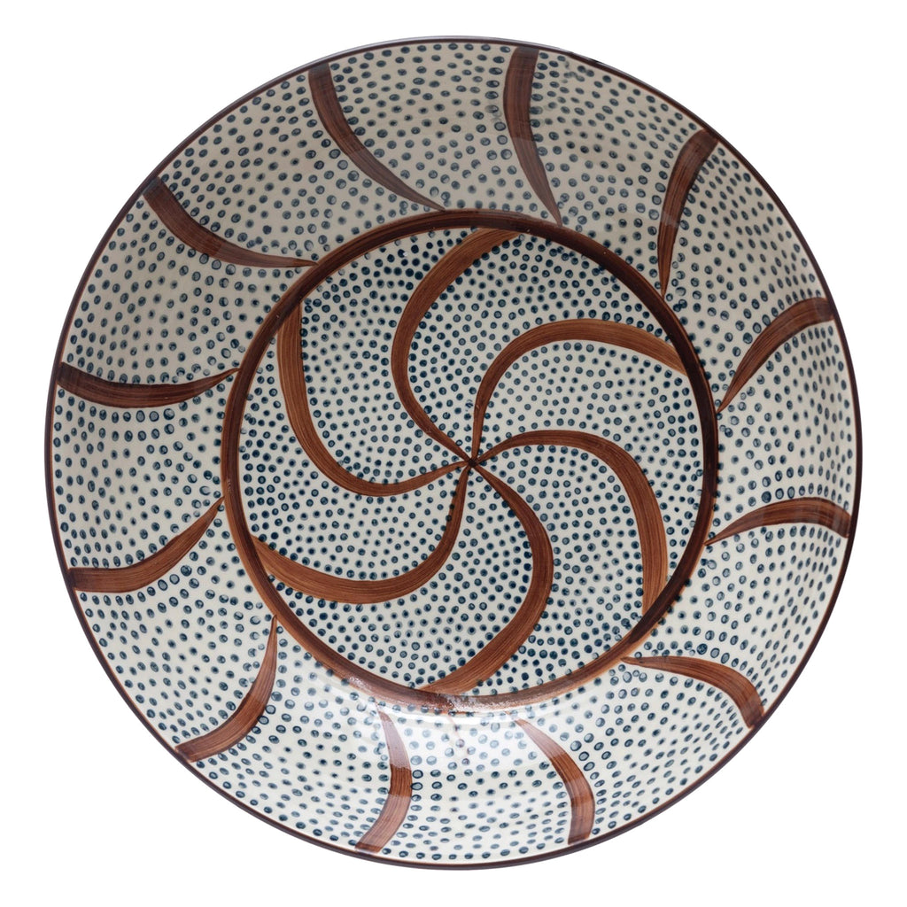 Creative Co-op large hand-painted stoneware serving bowl with brown swirls and blue dots on a cream backdrop, overhead view.