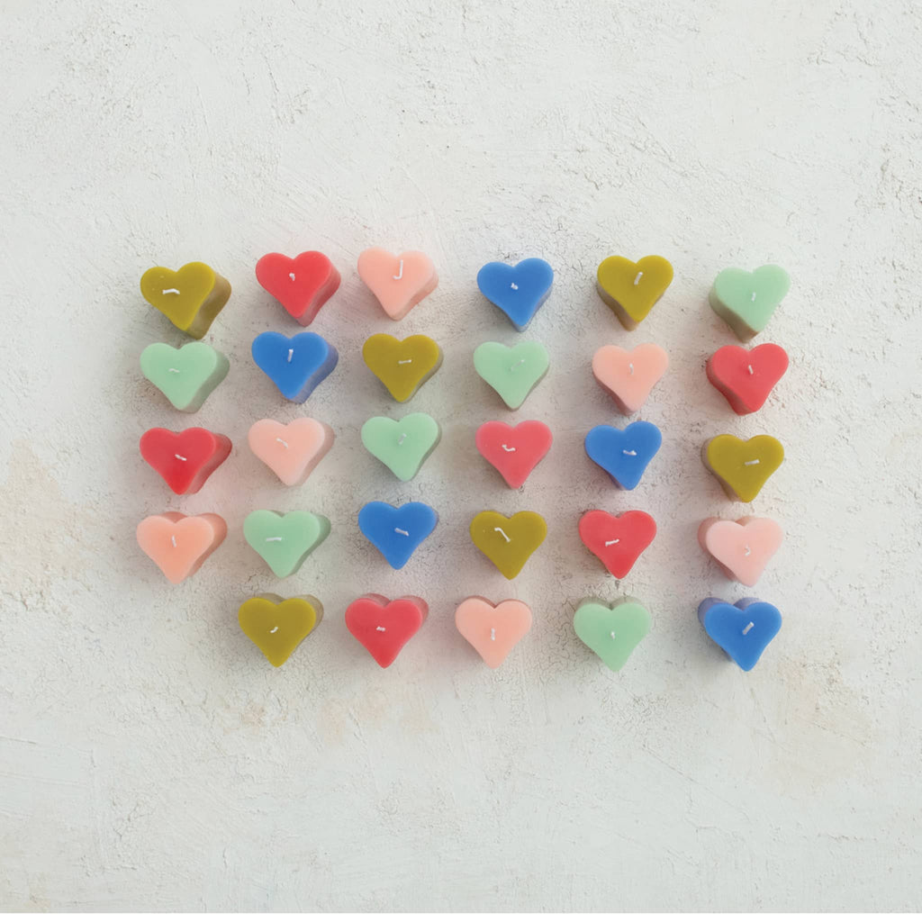 Heart-shaped candles in various colors arranged in a grid on a light background.