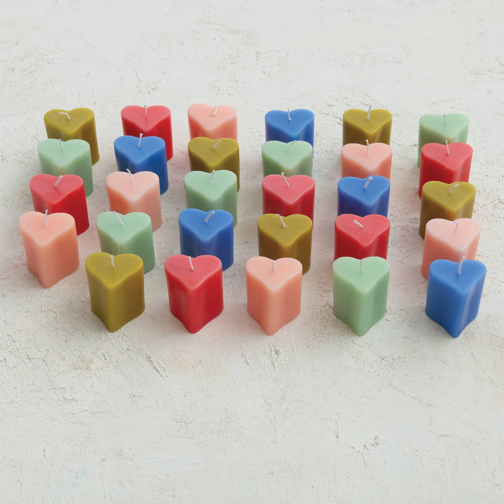 Colorful heart-shaped candles arranged in rows on a light background.