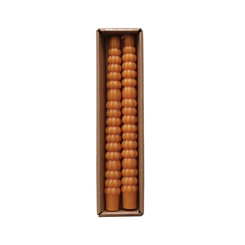 Two orange taper candles that look like stacked pumpkins in box packaging.