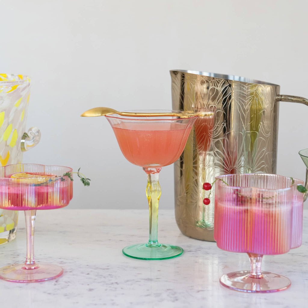 Creative Co-op Stainless Steel Pitcher with floral etched pattern and brass twig handle, shown with colorful cocktails in colorful glasses.