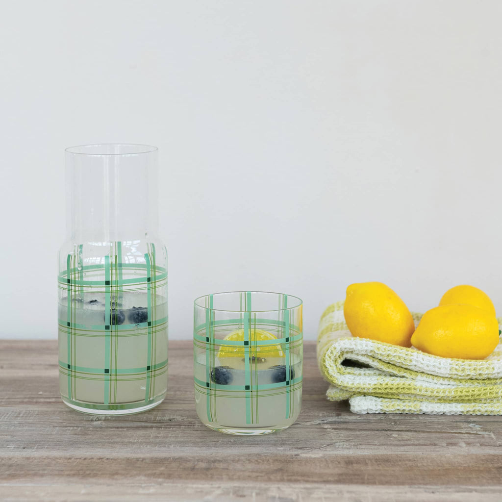 Creative Co-op Green Plaid glass carafe with matching drinking glass beside it, filled with lemonade on a wood surface.