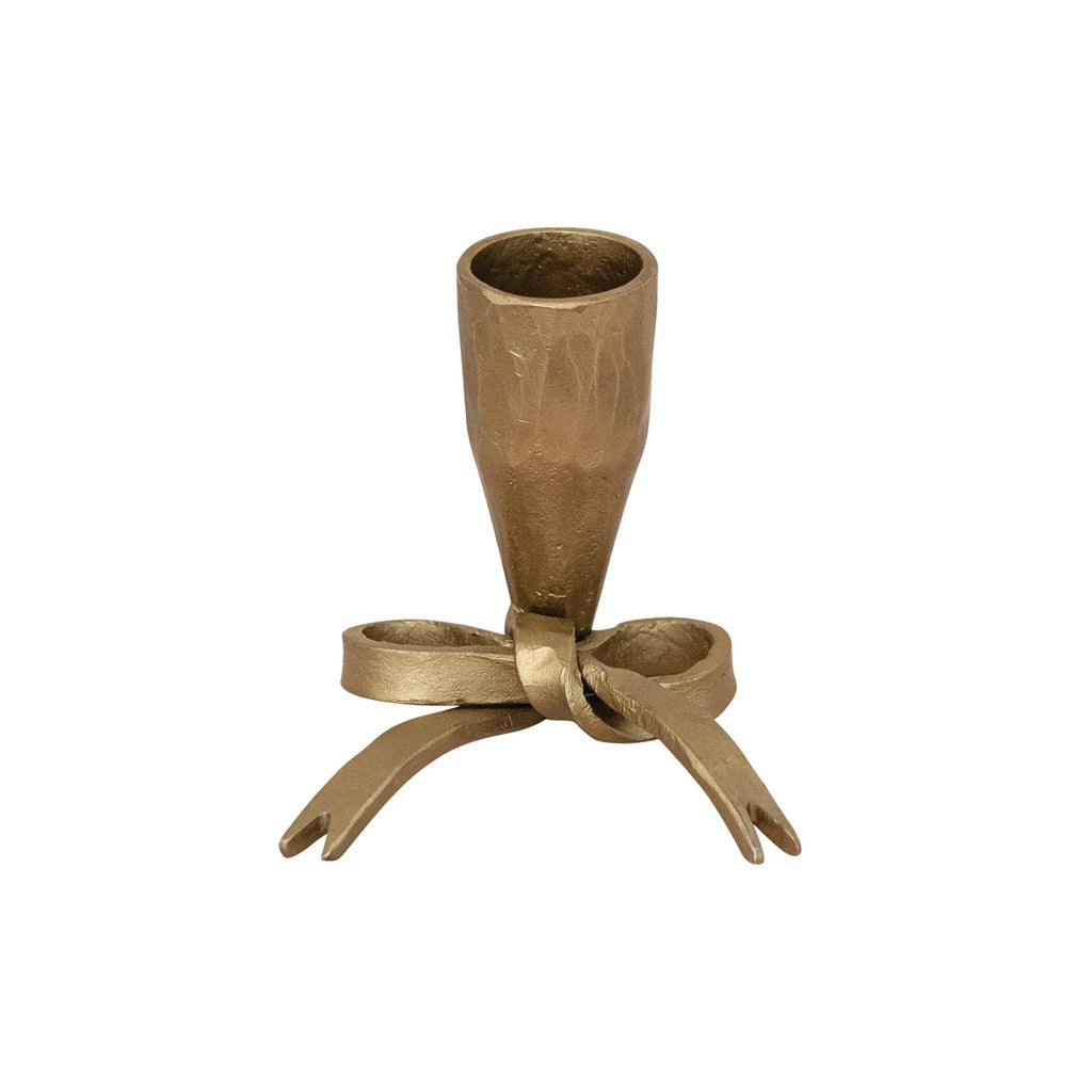 Antique gold finish cast iron candle holder with bow design on a white background.