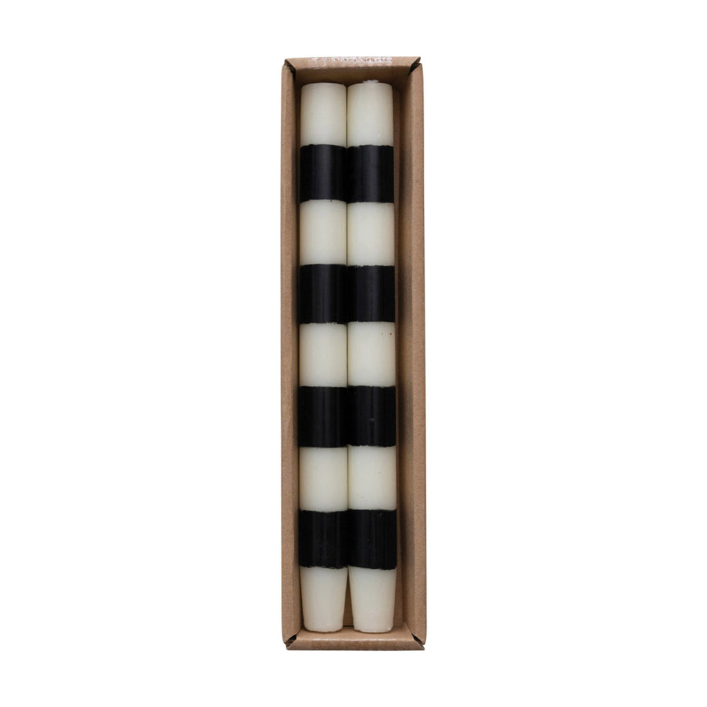 Set of black and white striped taper candles in a cardboard box on a white background.