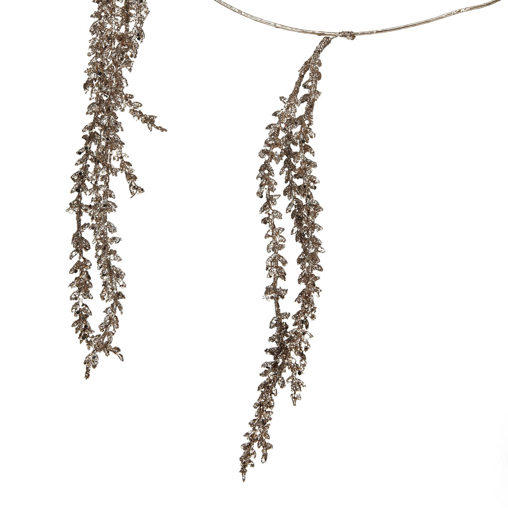 Decorative garland of tiny faux leaf strands in gold, detail, on a white background.