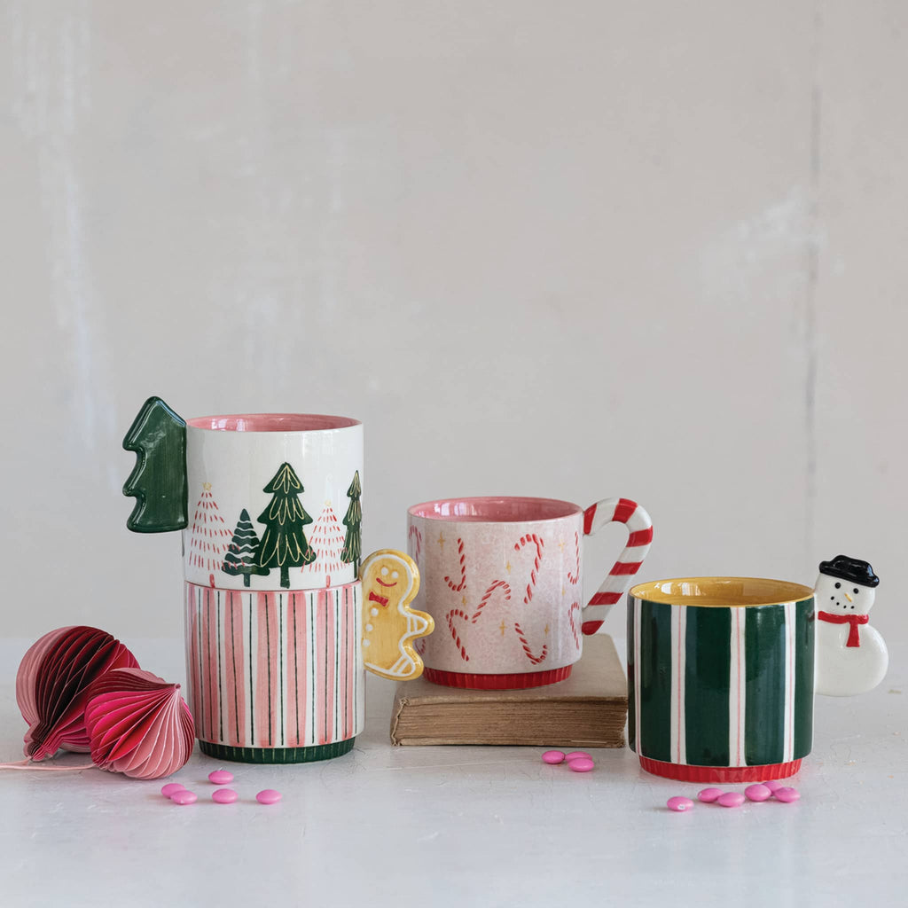 Set of Christmas-themed mugs and decorative items on a white surface.