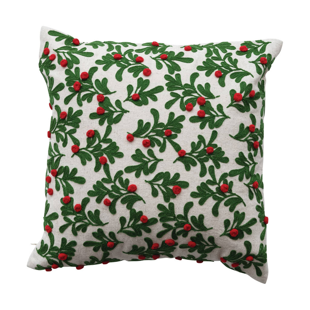 Decorative pillow with green leaf and red berry pattern on a white background.