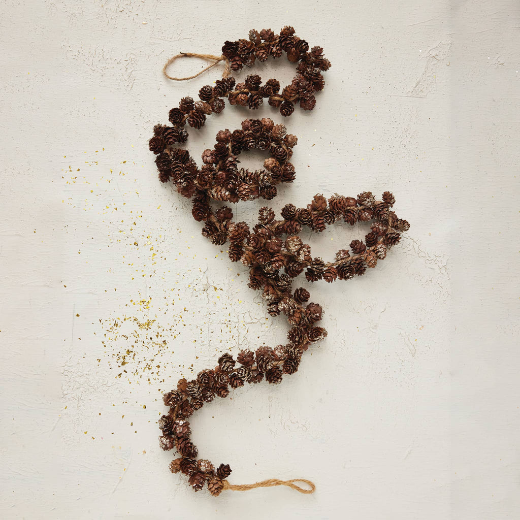 Pinecone garland with glitter and hanging loops at each end, full length curled up, on a white background.