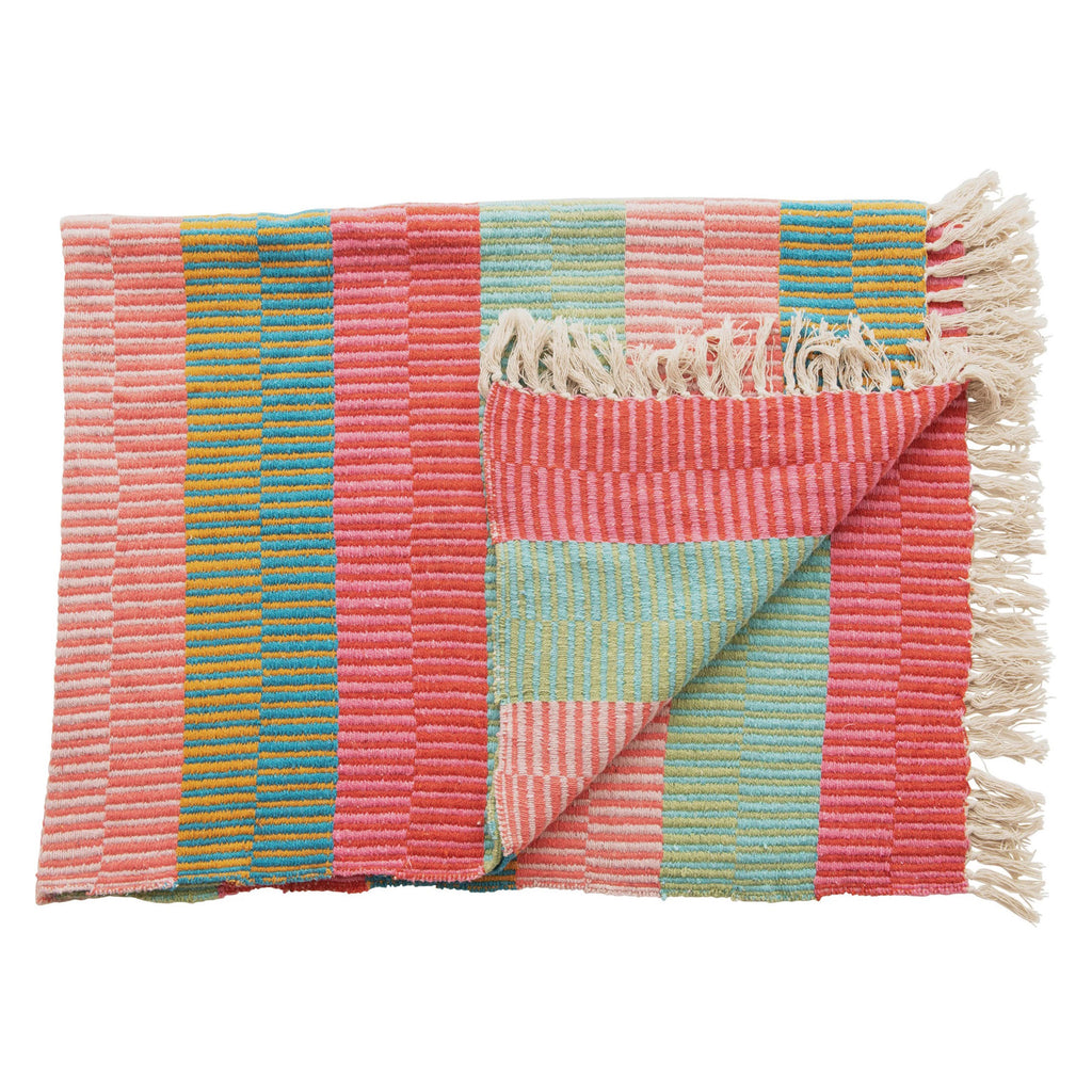 Creative Co-op Recycled Cotton Blend Striped Throw Blanket in shades of pink, turquoise, green, red and goldenrod with white tassel fringe at the top and bottom, folded with the corner pulled back to see reverse side.
